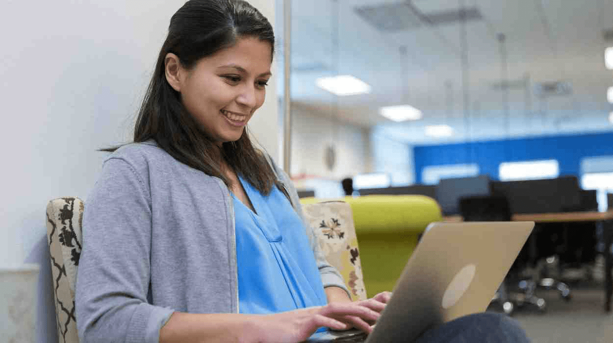 A pre-med student sitting in a computer lab working on her medical school personal statement on her laptop.